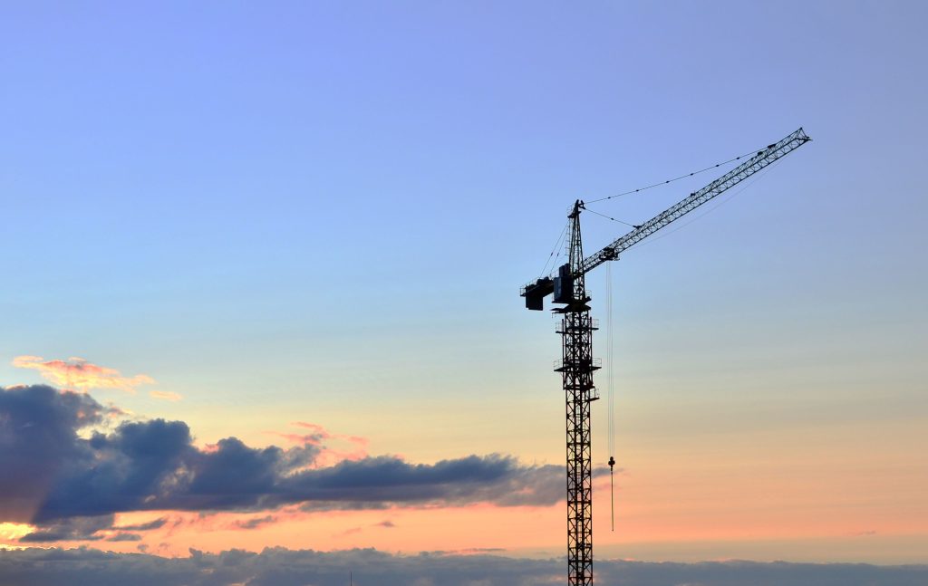 A crane against a blue and orange sky with a singular cloud.