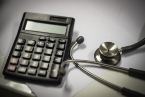 A calculator and a stethoscope sitting side by side on a desk