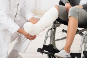 A doctor looks at a patient with their leg in plaster. 