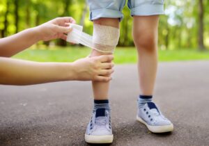 A child has their knee bandaged. 