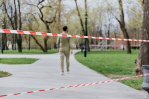 A jogger passes a taped off area in a park. 