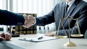 A solicitor and a client shake hands over a desk