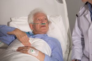 A patient lays on a hospital bed facing a medical professional. 