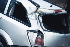 The back of a silver car destroyed from a split liability car accident.