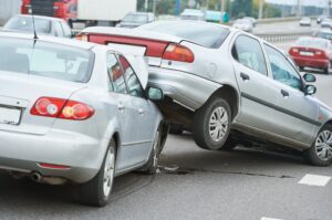 A silver car rear-ending and underneath the boot of another silver car.