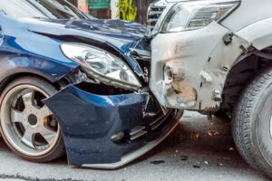 The bumper of a blue car and the bumper of a silver car crashed into each other.