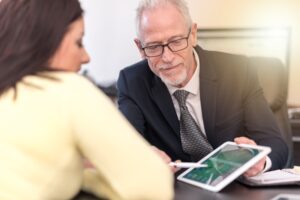 A solicitor shows a client a criminal injury compensation calculator on a tablet.