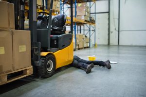 PERSON LAYING UNDER A FORKLIFT TRUCK AFTER AN ACCIDENT AT WORK