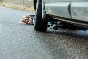 A child is motionless in the road having been hit by a car.