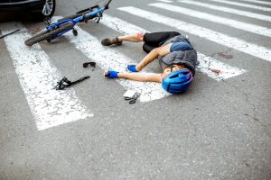 A man lying in the road on a zebra crossing after being knocked off his bicycle