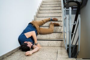 A person lays at the bottom of a staircase after a fall.