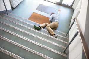 A man lays at the bottom of a staircase. 