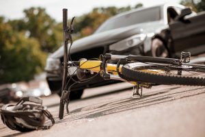 A bicycle and helmet lying in the road in front of a car