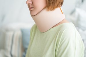 A woman with a neck injury. She has a soft collar around her neck.