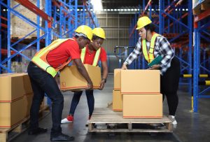 Workers lifting boxes using health and safety regulations.